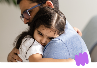 Father holding and comforting toddler daughter who is ill