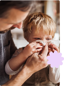 Father looking after toddler son blowing nose