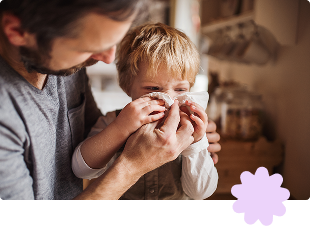 Father looking after toddler son blowing nose