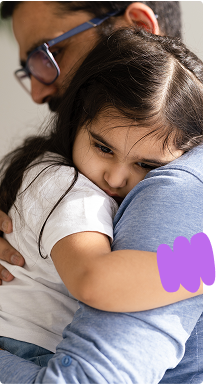 Father holding and comforting toddler daughter who is ill