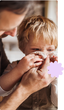Father looking after toddler son blowing nose
