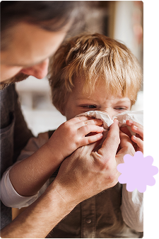 Father looking after toddler son blowing nose